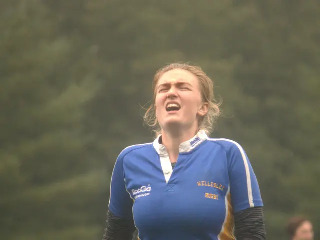 In this image we can see a woman wearing a rugby t shirt. The background is unclear and we can also...