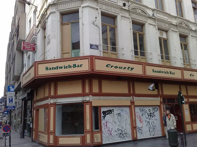 In the image there is a building with walls, windows, glass doors, railings, name boards and...