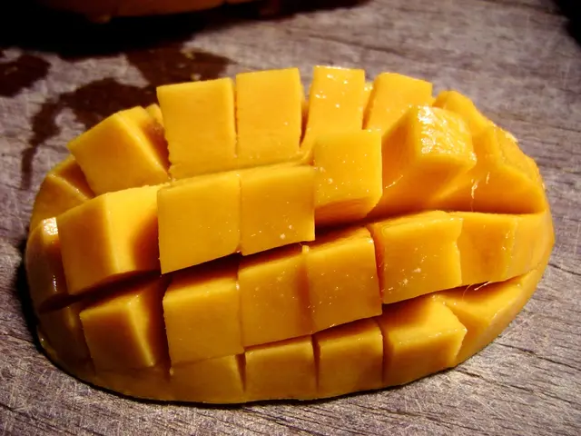 We can see mango slices on the wooden surface.