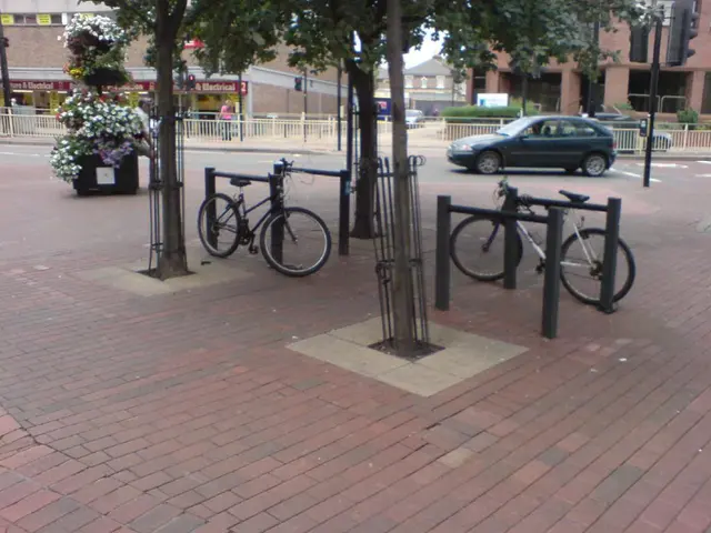 As we can see in the image there are bicycles, trees, fence, car and buildings.