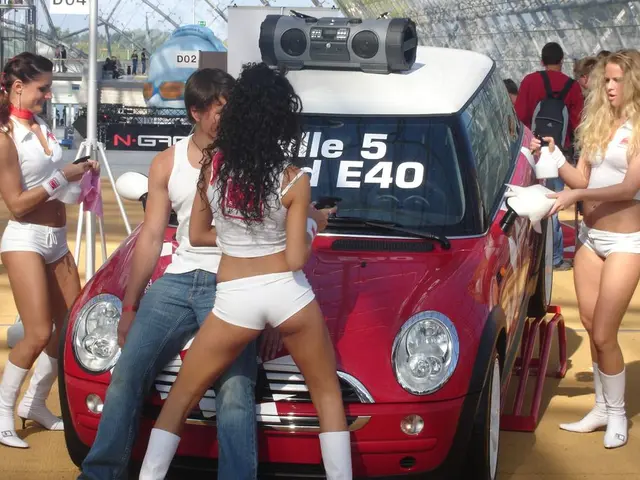 In the image there is a red car in the middle with three women in white bikini standing around it...