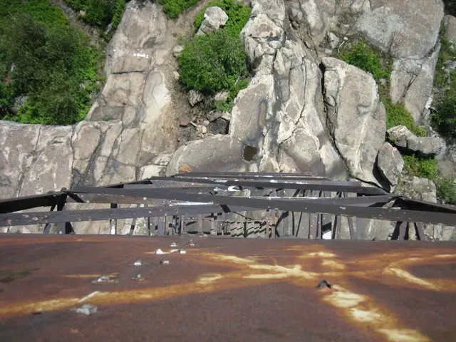 In this image, we can see the metallic surface and some metal rods. We can also see some rock hills...