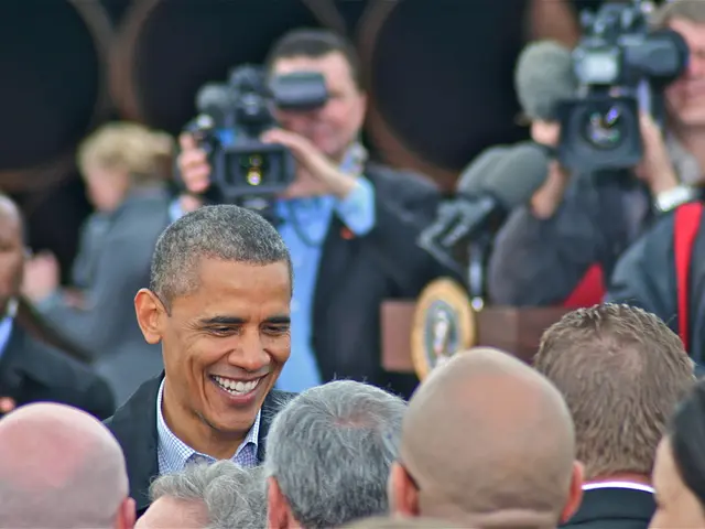In this image there is a man in the middle who is talking to the people who are in front of them....