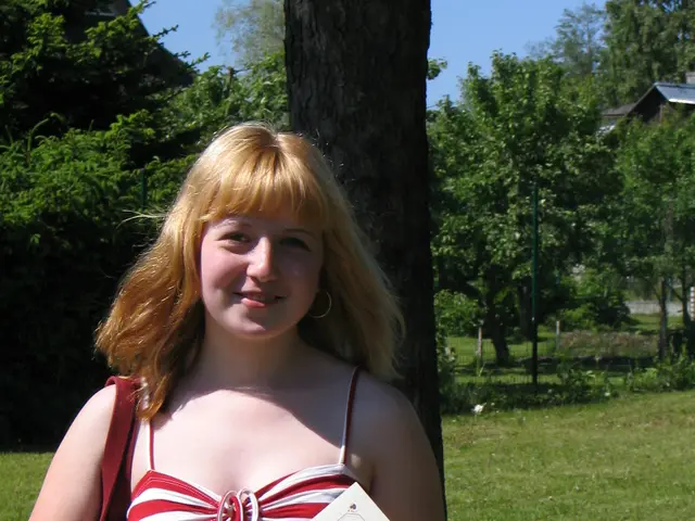 In the image there is a woman in golden hair and red vest standing in front of tree holding book on...